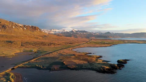 Aerial approach over highland lagoons toward snow-dusted mountains. Iceland Stock Footage 345164341