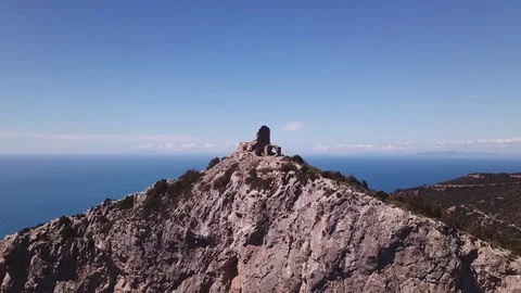 Aerial approach to a peak with Tower on a cliff by the sea, some trekkers on it Stock Footage 107180599
