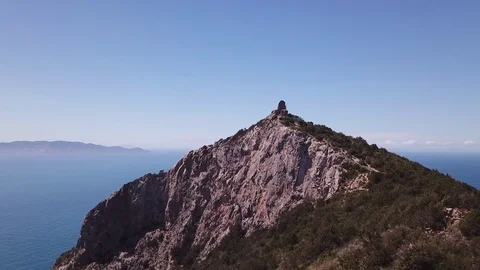 Aerial approach to a peak with Tower on a cliff by the sea, sunny day Stock Footage 107180852