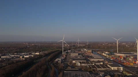 Aerial approach to single wind turbine over port in warm evening light Stock Footage 335651698