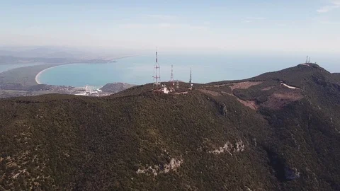 Aerial approach to a trellis structures on a peak with the seacoast at  distance Stock Footage 105242560