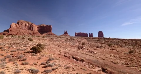 Aerial: approaching and rising to view Monument Valley over desert floor Stock Footage 100613555