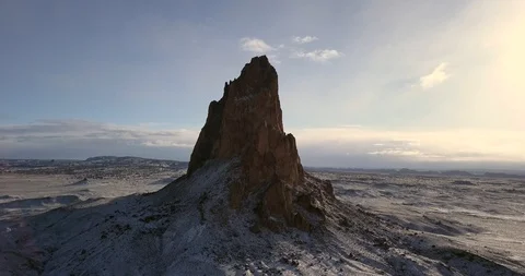 Aerial - approaching imposing bare mountain peak over a field of snow Video stock 106482502