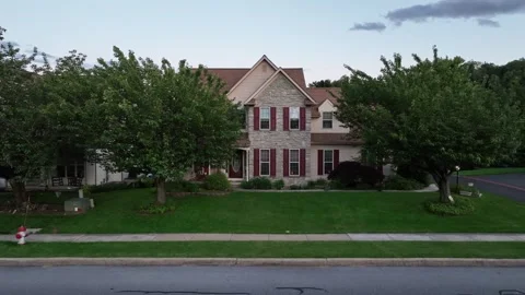 Aerial approaching shot of brick single family house with green yard and green 動画素材 312250451