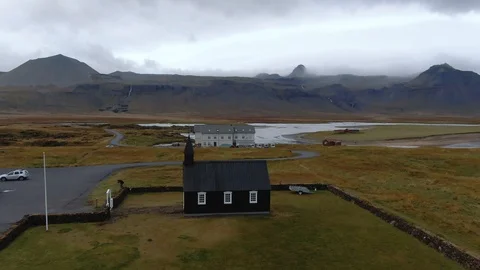 Aerial approaching view of a small black church and a graveyard in West Iceland Stock Footage 115711379