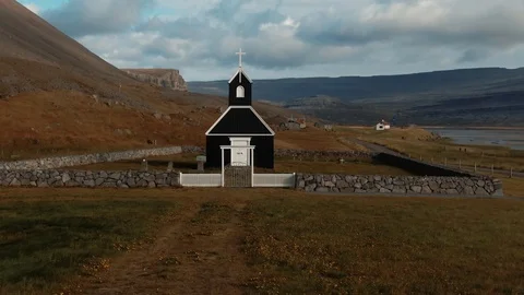Aerial approaching view of a small black church in a fjord in West Iceland Stock Footage 116543501