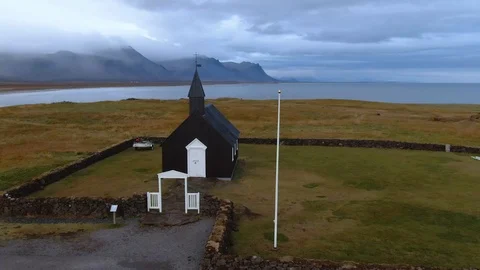 Aerial ascending view of a small black church in a fjord in West Iceland Stock Footage 116183574
