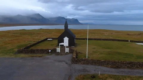 Aerial ascending view of a small black church in a fjord in West Iceland Stock Footage 118945754