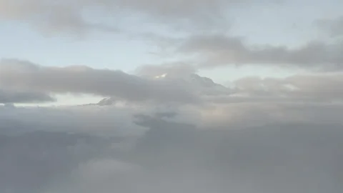 Aerial ascends from clouds to reveal Mount Rainier blanketed by clouds at sunset Stock Footage 345171291