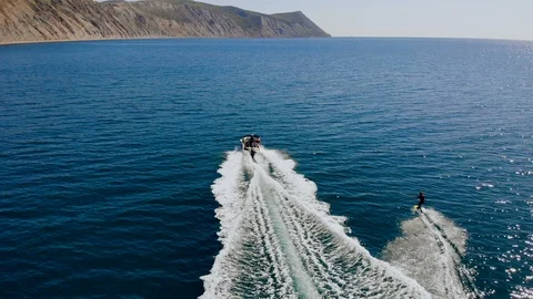 Aerial back view of a young man wakeboarding pulled by a speedboat on an Stock Footage 102374998