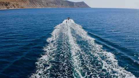 Aerial back view of a young man wakeboarding pulled by a speedboat on an Stock-Footage 102375948