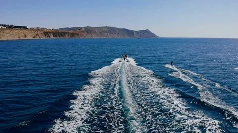 Aerial back view of a young man wakeboarding pulled by a speedboat on an Video stock 102376830