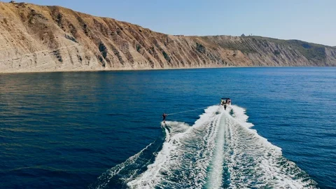 Aerial back view of a young man wakeboarding pulled by a speedboat on an Stock Footage 102378856