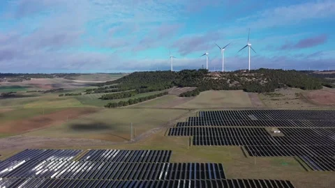 Aerial backward flight over solar panels and wind turbines in rural landscape 库存影片 327450280