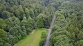 Aerial backwards flight shot small street and meadow within woodlands (1/4) 4k or 4k+ Resolution