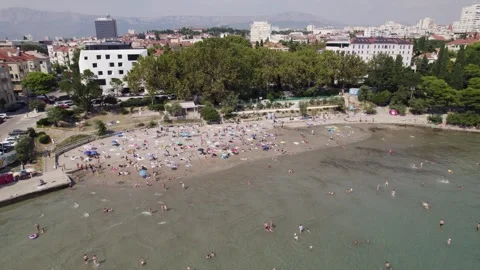 Aerial: Bacvice Beach, Split, Croatia with sunbathers and city backdrop Stock Footage 253883931