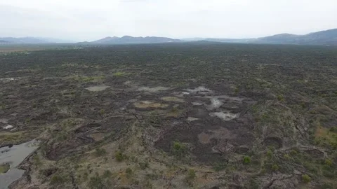 Aerial basalt lava plain with lake water and dark - Texture and Mineral Surface Stock Footage 339407818