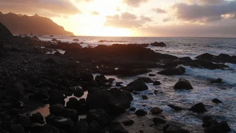 Aerial. Beach at sunset. The view opens to black stones and volcanic sand, the Stock Footage 109261693