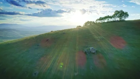 Aerial beautiful green grass pastures mountain valley horizon sun beams sky Stock Footage