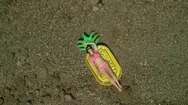 Aerial: Beautiful Woman Sunbathing Riverside On A Pineapple Shaped Floatie. Stock Footage