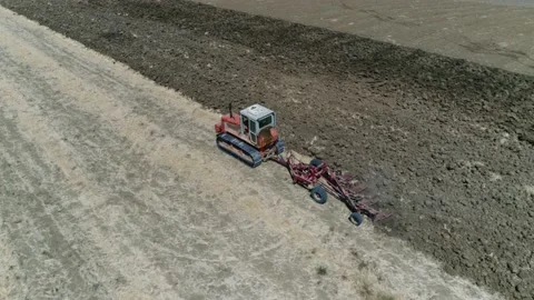 Aerial bird view of continuous track tractor plowing rough soil 4k Stock Footage 237361541