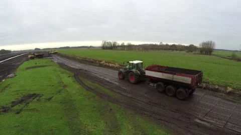 Aerial bird view of tractor pulling trailer picking up a load of sand mud 4k Stock Footage 59574527