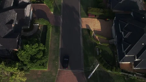 Aerial of Black Car driving down street - Birds eye view Stock Footage 87724597