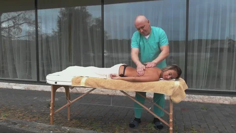 Blonde woman relaxing receiving back massage from male