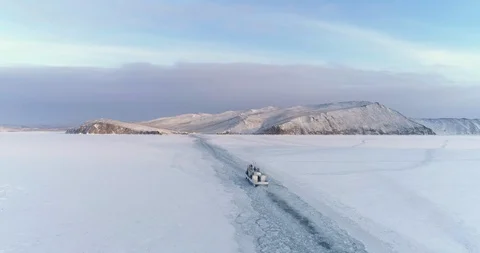 Aerial Boat Float Along Empty Snow Covered Surface of Frozen Lake Baikal. Drone Stock Footage 128940763