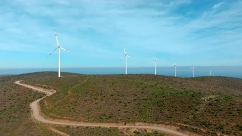 Aerial boom up view of a string of wind turbines on a sunny day in the Video stock 213518058