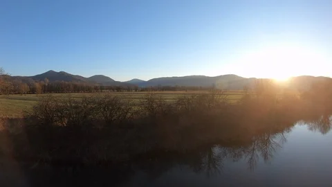 AERIAL Calm river surface and sunset behind the hills Stock Footage 101074887