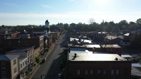 Aerial camera flying into the sun, low over houses along the mainstream in Stock Footage 129620141