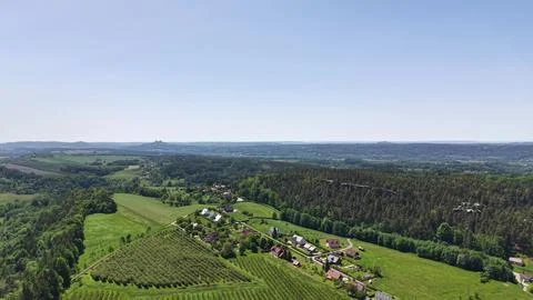 Aerial camera gliding over patchwork fields, forest edges, and distant hill.. Stock Photos