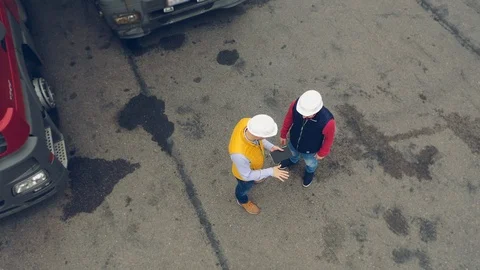 AERIAL. Camera moving around Two workers, two drivers works on tablet near Stock Footage 111405054