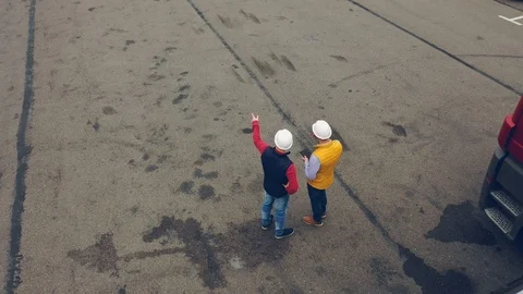 AERIAL. Camera moving around Two workers, two drivers works on tablet near Stock Footage 111405073