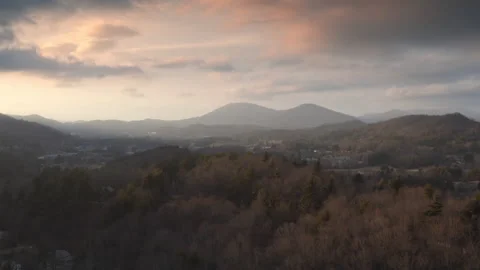 Aerial - Camera rises over hillside revealing sunset over cold mountains Stock Footage