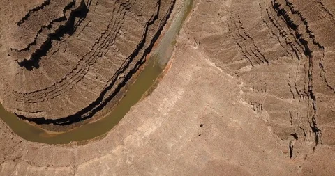 Aerial: camera tilts up from deep river canyon to desert landscape Stock Footage 99445522