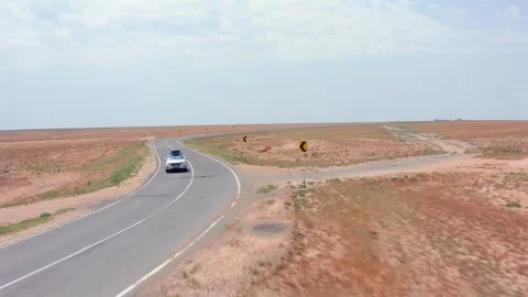 Aerial camera tracking car approaching junction front view along curved asphalt Stock Footage 334027972