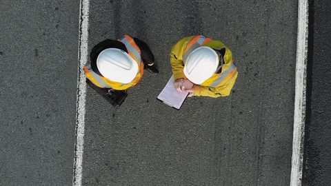 AERIAL. Camera zooming out. Image of two workers standing and talking at Stock Footage 101228737