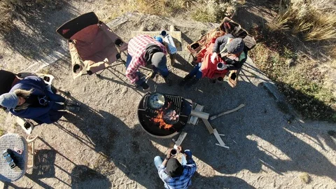 Aerial of camp fire while campers prepare cooking breakfast Stock Footage 122093773
