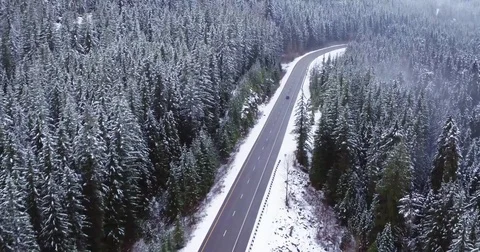 Aerial of car driving up mountain pass snow covered trees Stock Footage