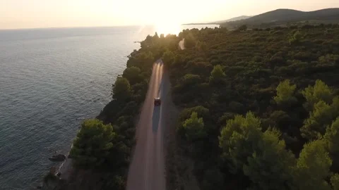 Aerial of car driving near the sea during sunset Stock Footage