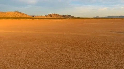Aerial of a car passing by on a desolate dry lake in the desert Stock Footage 81225881