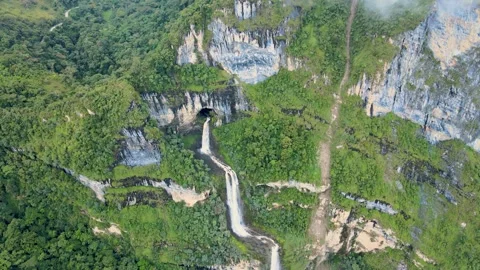 Aerial cave waterfall cascading down green limestone cliff Stock Footage 331410639