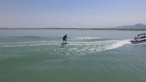 Aerial chasing over wake surfer hydrofoil wake boarding behind a boat Stock Footage 102689175