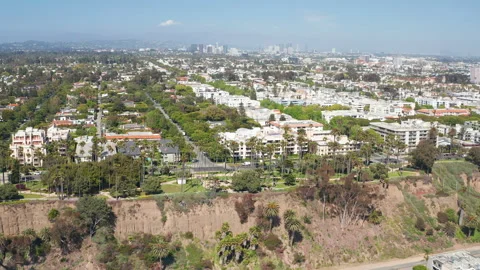Aerial cinematic pullback view of Santa Monica Los Angeles homes tree skyline Stock Footage 308131097