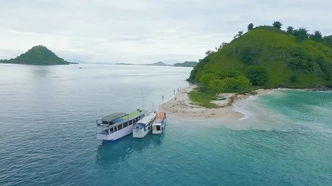 Aerial circle around view blue ocean, boats, trees and white sand. Labuan bajo i Stock Footage 129678542