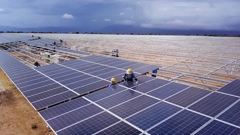 Aerial circle shot of workers installing panels in a solar farm Stock Footage