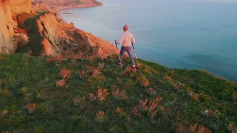 Aerial circle view of a young man hiking on the cliff at the seaside enjoying Видео 111950481