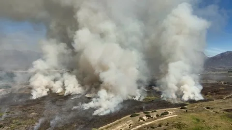 Aerial circles grass fire on mtn plateau filling sky with thick smoke Stock Footage 343348940